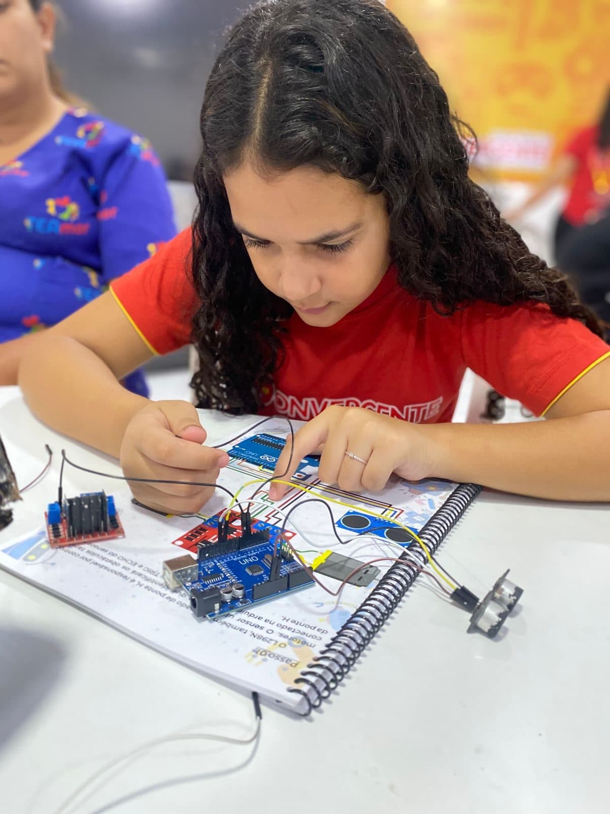 Aluno ajustando placa Arduino em projeto de robótica