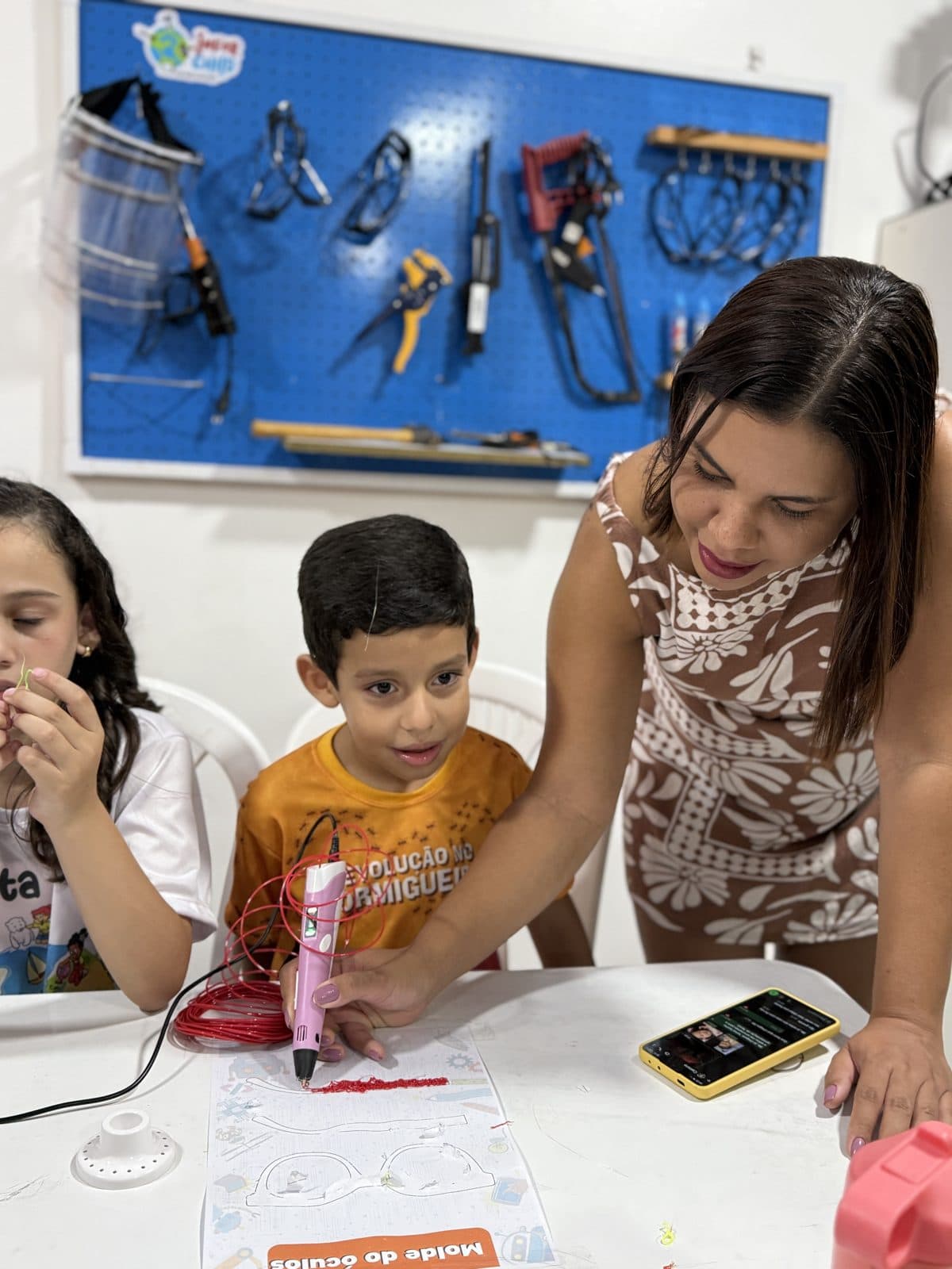 Professora orientando alunos em projeto maker